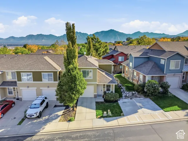 Mountain backdrop, townhome-style residences, attached garages, paved driveways, and established landscaping