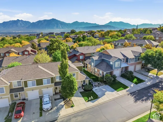 Modern residential community with pitched roofs, individual garages, landscaped front yards, concrete driveways, and sidewalks