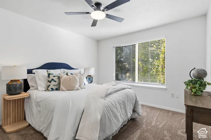 Spacious room featuring a ceiling fan with integrated lighting, a large window with blinds, and neutral carpet flooring