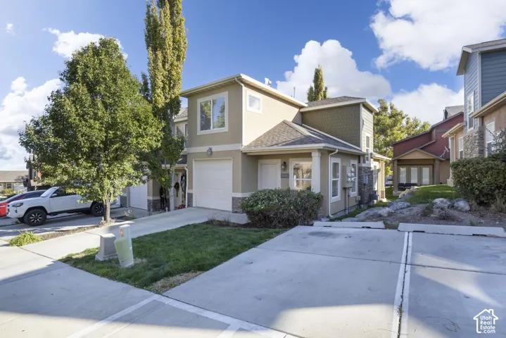 Two-story exterior with a garage, stone-finish accents, and a sloped roofline