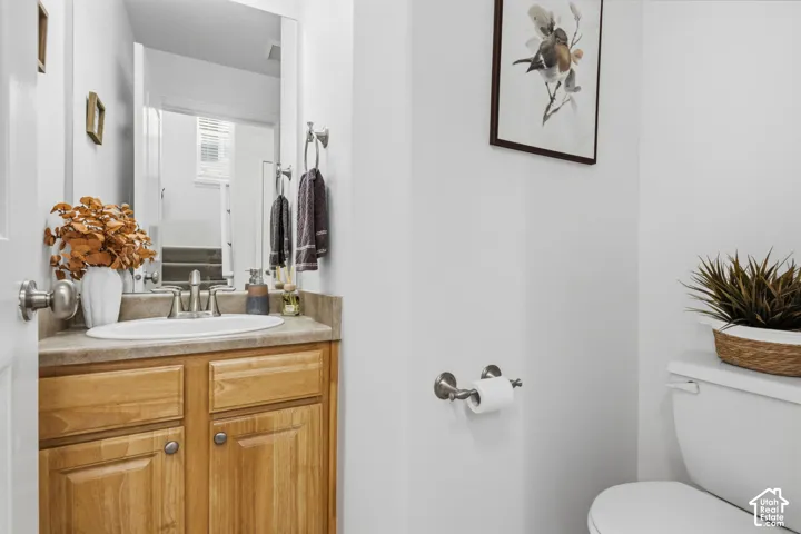 Elegant bathroom featuring warm wood-finish cabinetry with dual hardware pulls, ceramic vessel sink with brushed nickel faucet and fixtures, light stone countertop, and white subway tile walls