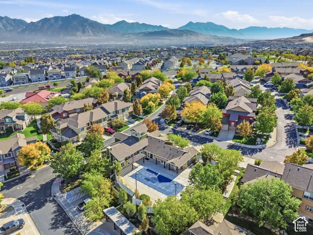 Community with mountain backdrop, residential structures, mature trees, and a central swimming pool