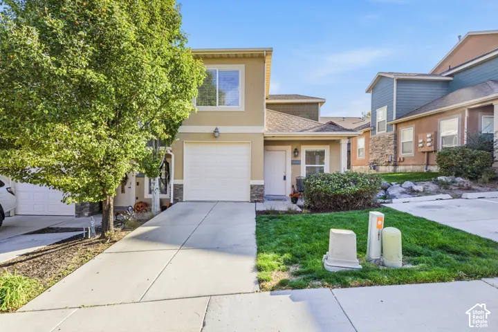 Two-story exterior with stucco and stone accents, attached garage, concrete driveway, and a well-maintained lawn