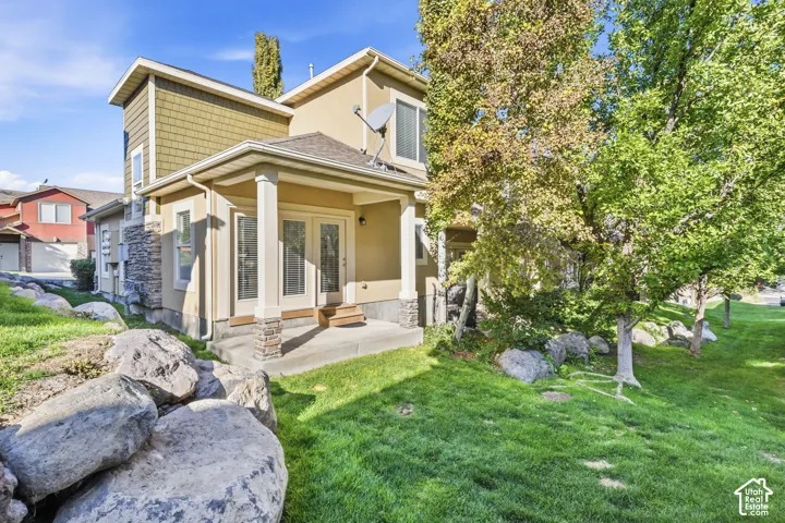 Covered patio with double doors, stone-clad columns, and stone accents