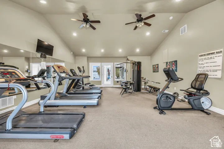 Fitness room featuring a vaulted ceiling, recessed lighting, dual ceiling fans, wall-to-wall mirror, and neutral carpeting