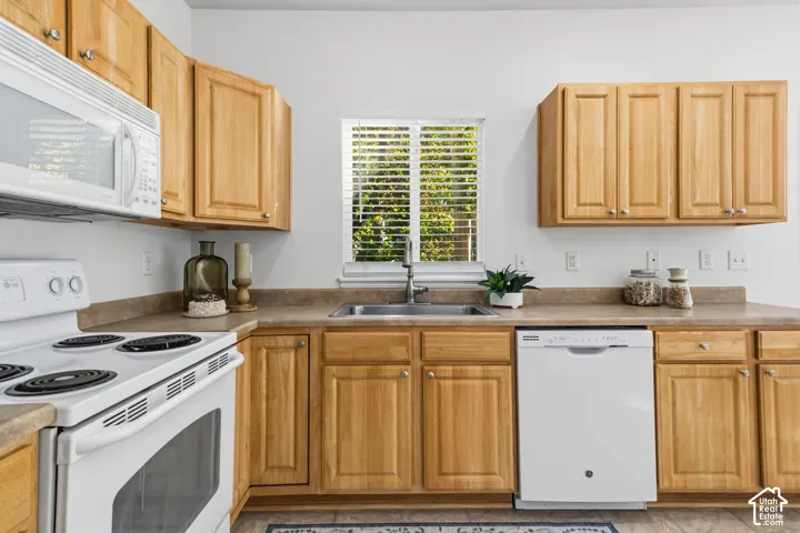 Kitchen featuring a built-in microwave, white electric range, wood cabinetry, and a stainless steel sink with a window above