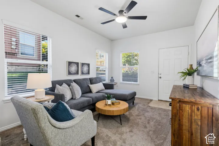 Bright living room showcasing a curved accent chair, sectional sofa, and round wood-finish cocktail table anchoring the space
