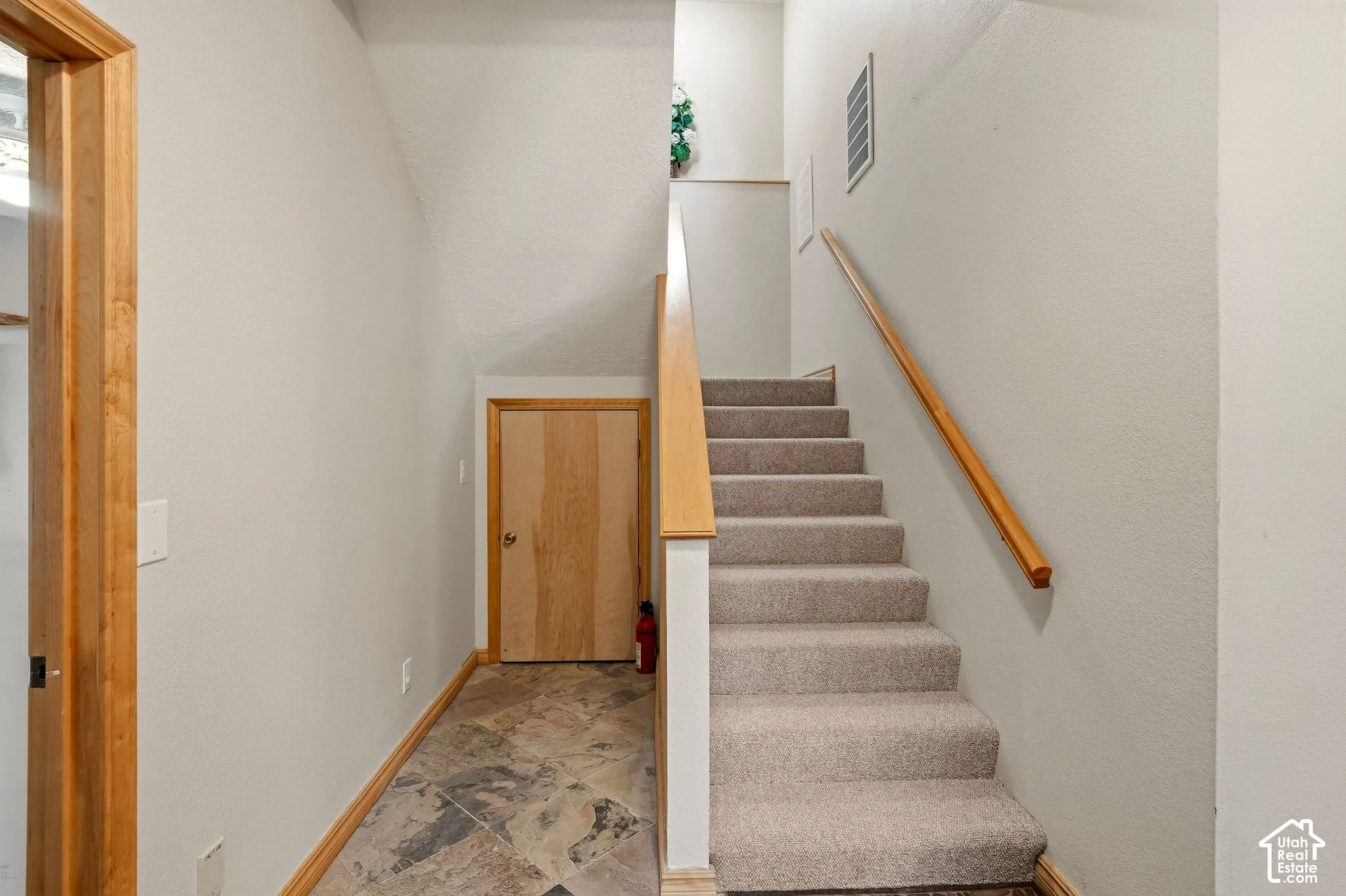 Carpeted staircase with wood handrail