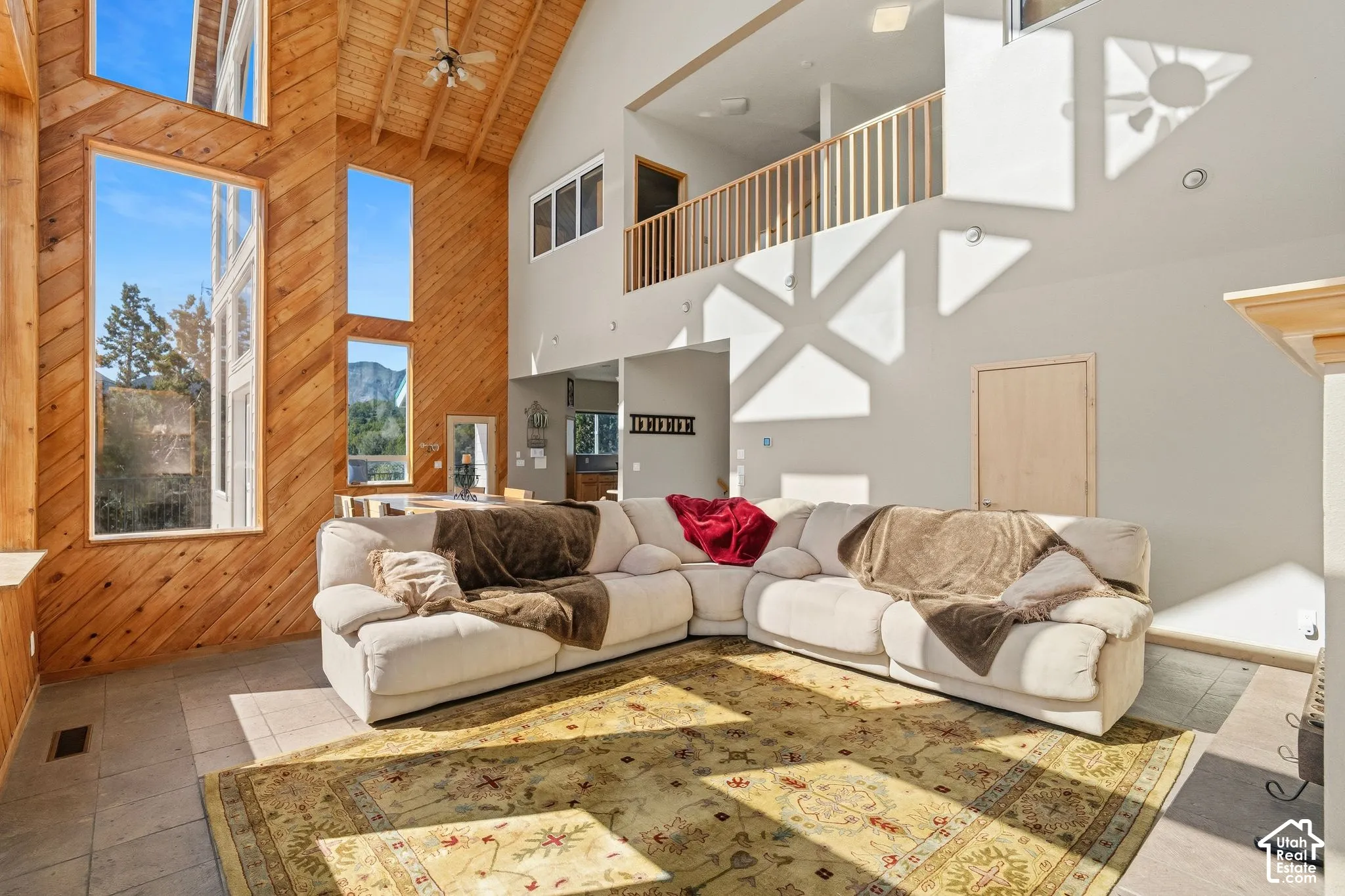 Soaring vaulted wood-beam ceilings and expansive fixed windows flood this living space with natural light