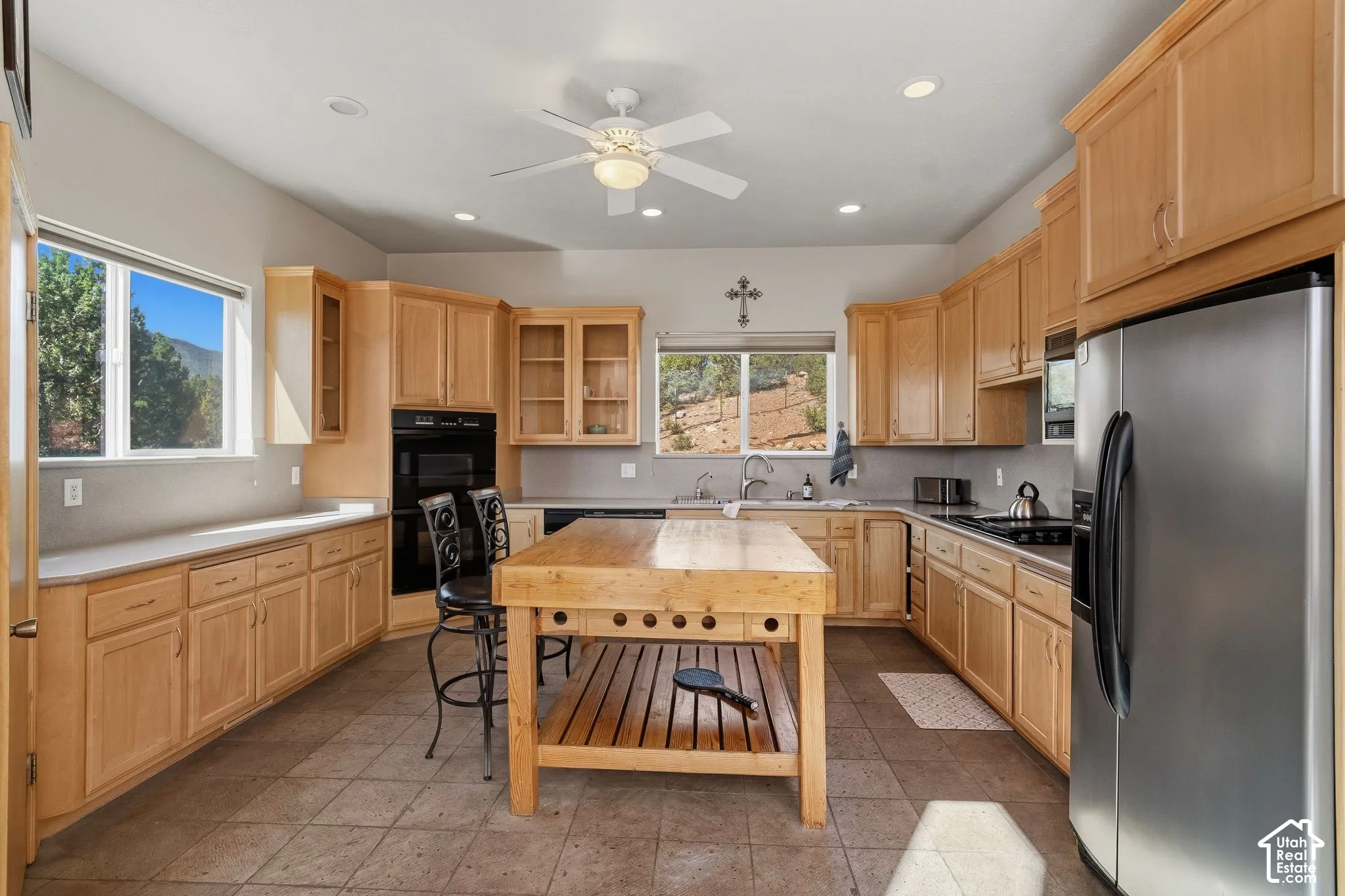 Kitchen featuring extensive wood cabinetry, a central wood-finish island, stainless steel appliances, and tiled flooring