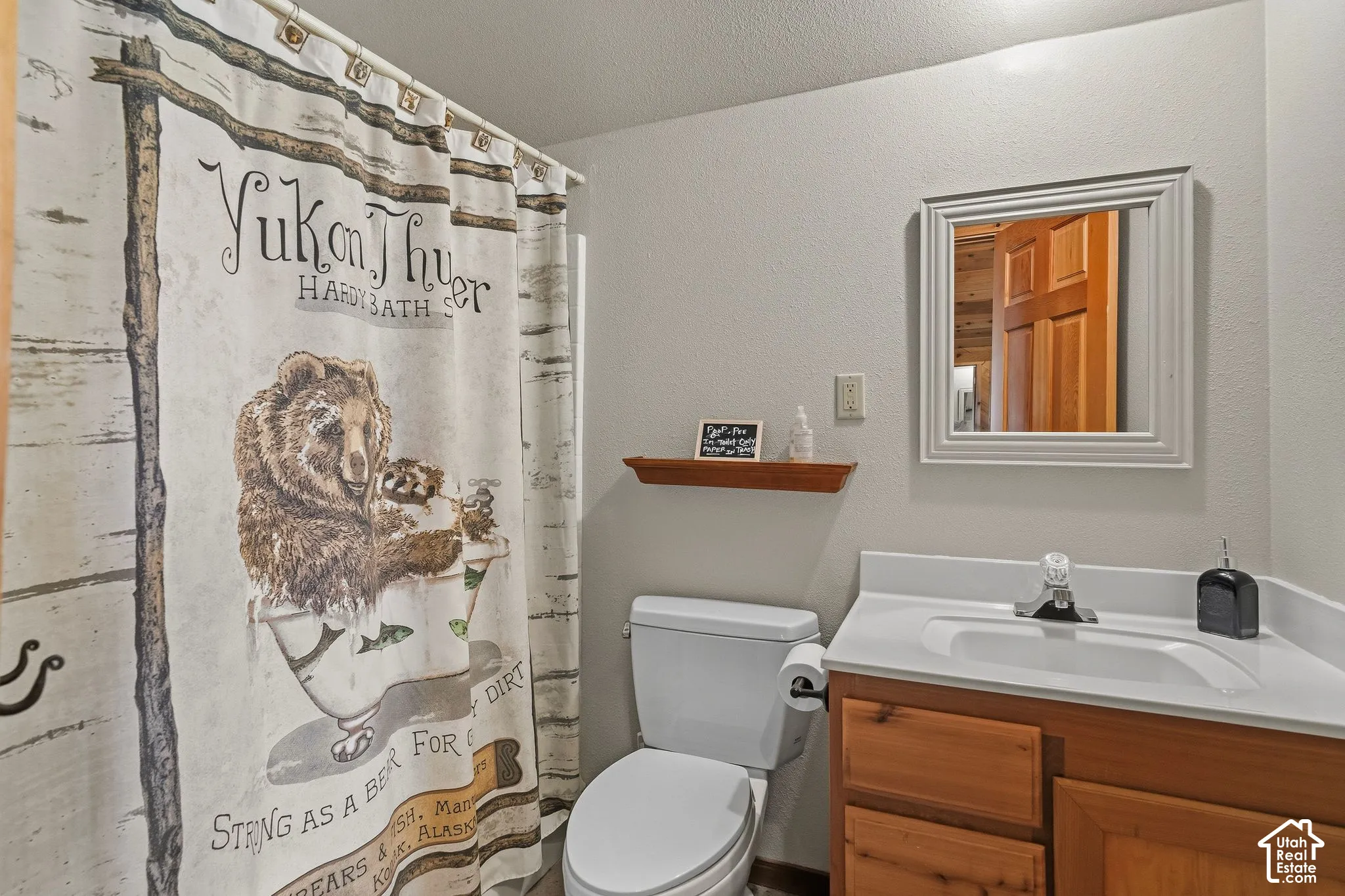 White single-basin vanity with a light wood-finish cabinet and a framed mirror