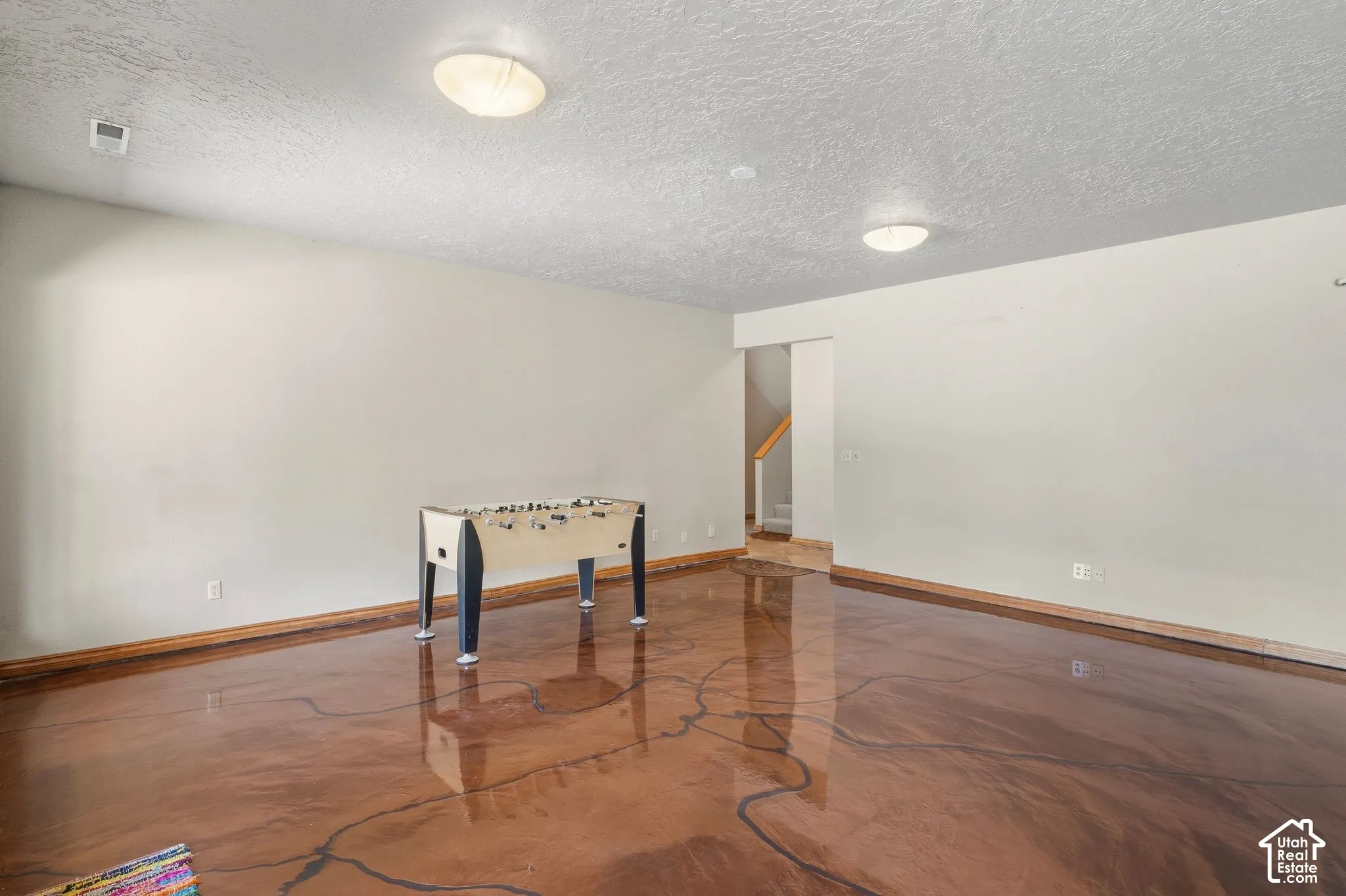 Spacious room featuring a polished concrete floor, light-toned walls, and recessed lighting