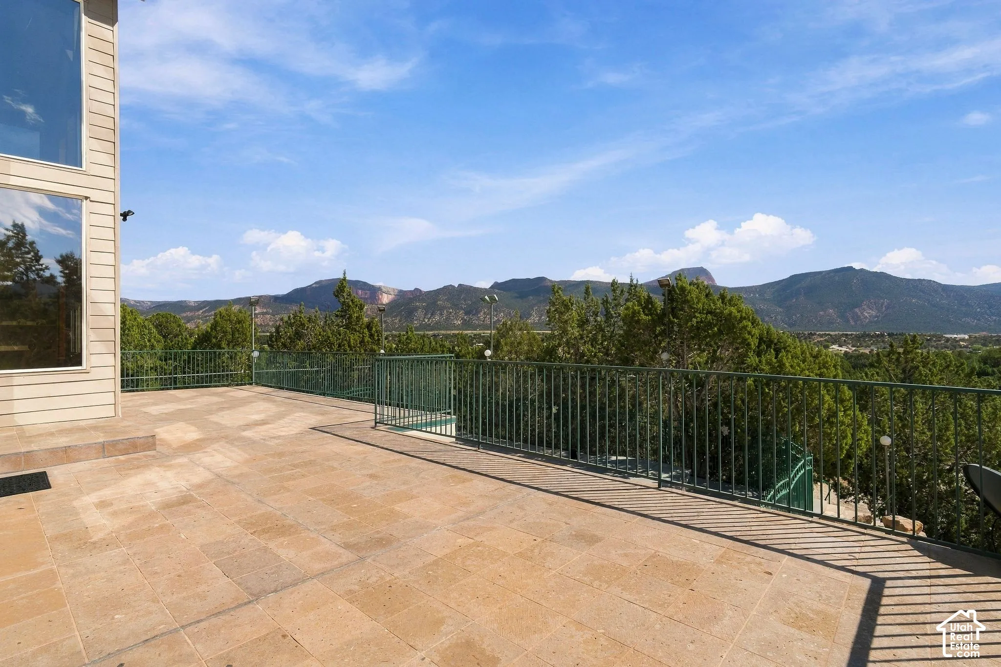 Expansive stone-paved terrace overlooking manicured landscaping and forested mountain ranges