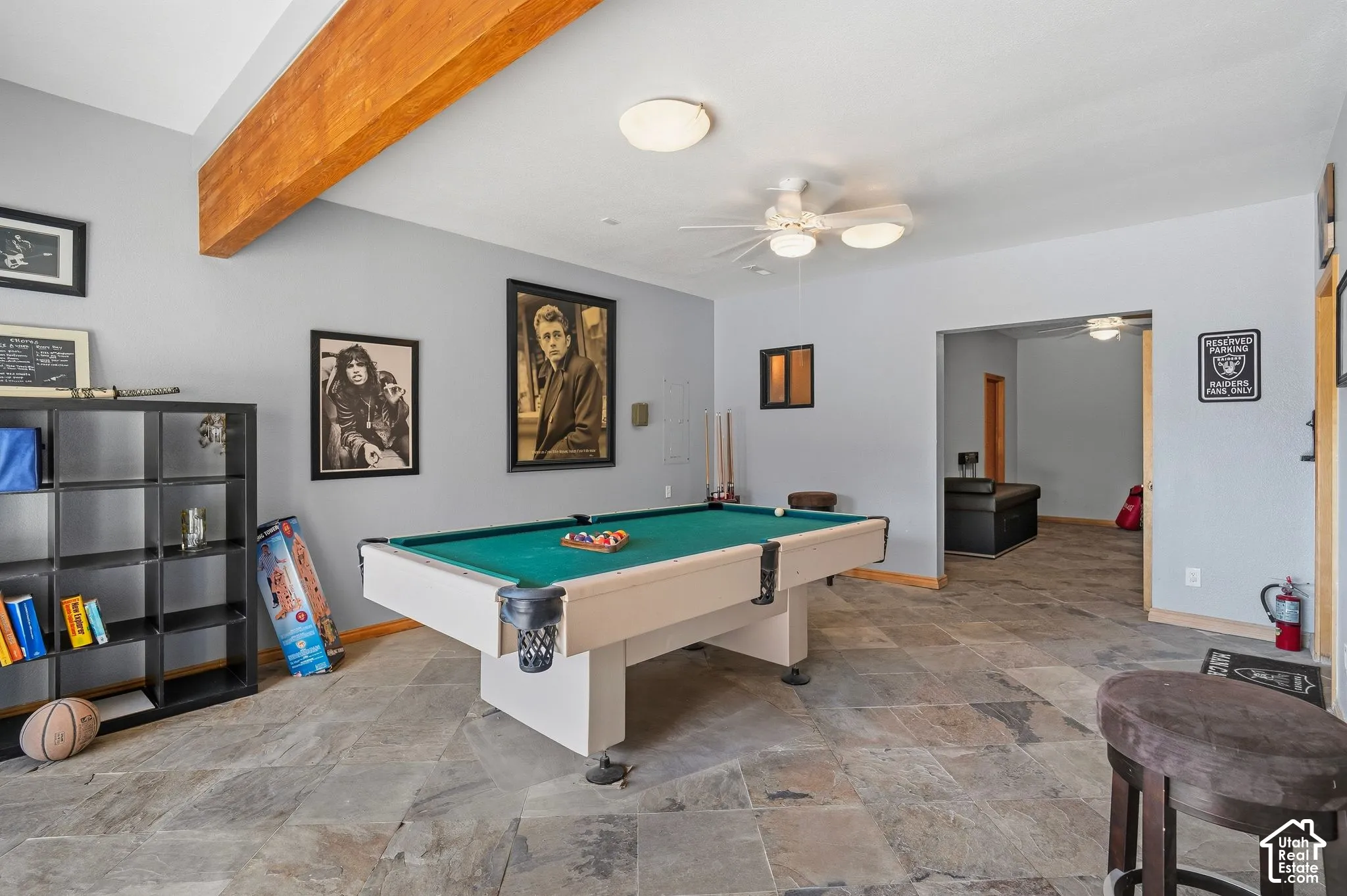 Recreational room featuring a regulation pool table with teal felt, polished concrete flooring, recessed and ceiling fan lighting, exposed wood beam detail, built-in shelving with display space, and access to adjacent rooms through multiple doorways