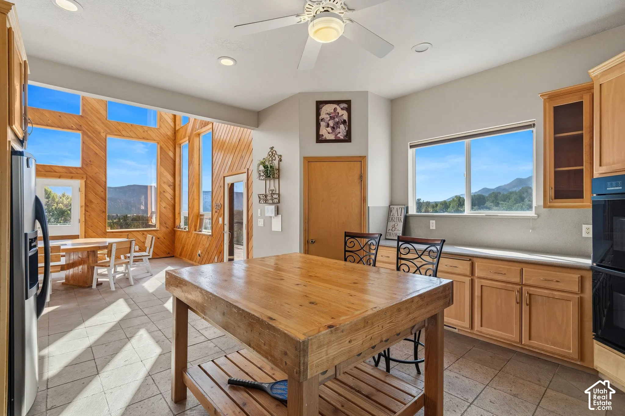 Bright, sun-filled kitchen featuring wood cabinetry, tile flooring, and a substantial wood-finish center island with seating