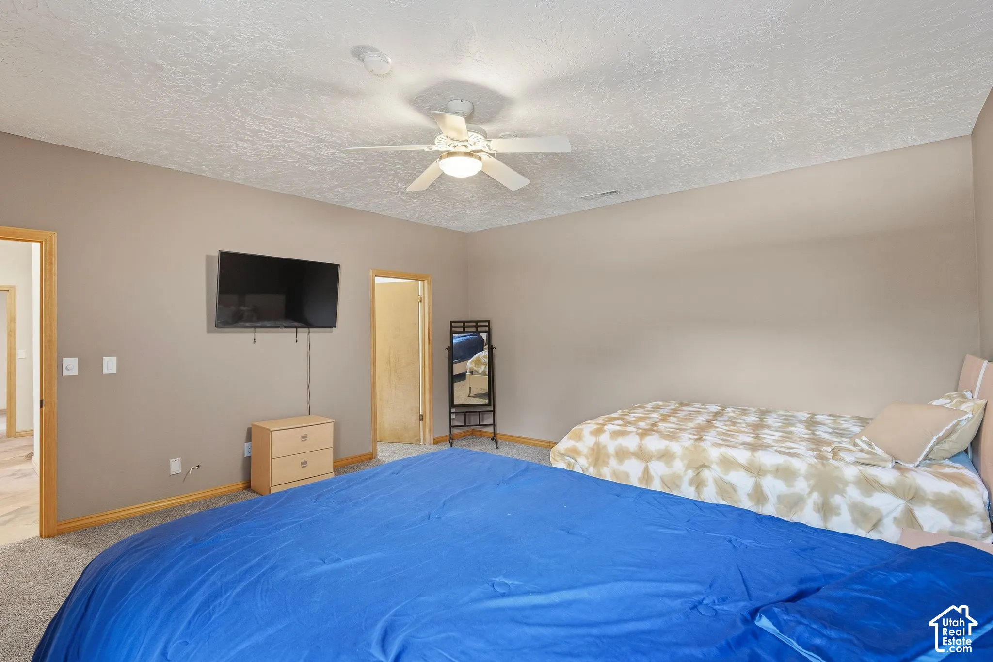 Neutral tone walls, ceiling fan with integrated lighting, and carpet flooring