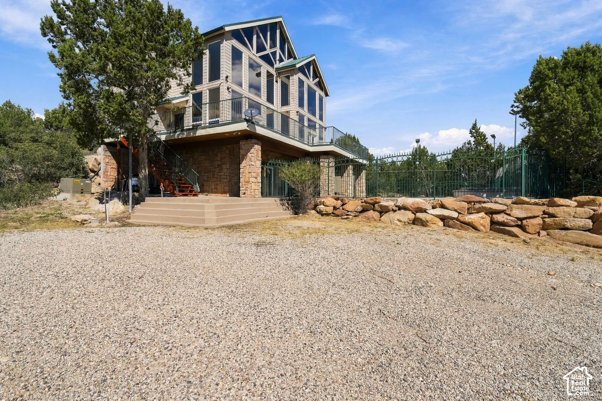 Multi-level property with expansive window elements, glass panel balcony, and stone facade