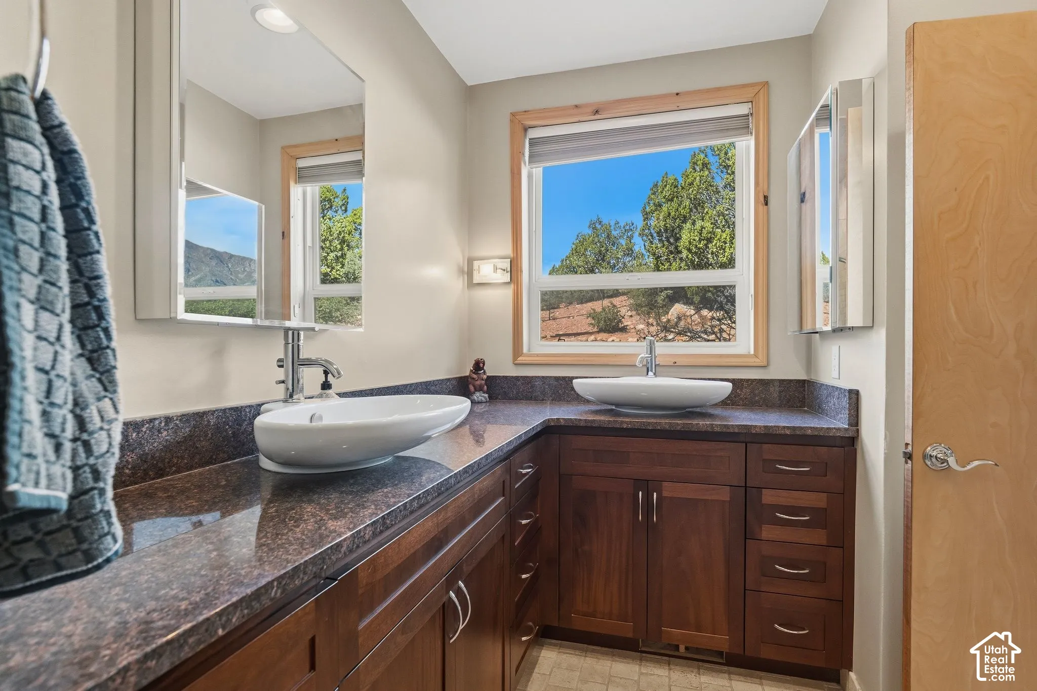 Spa-inspired dual-sink vanity with dark-stained wood cabinetry, stone countertops, and vessel sinks