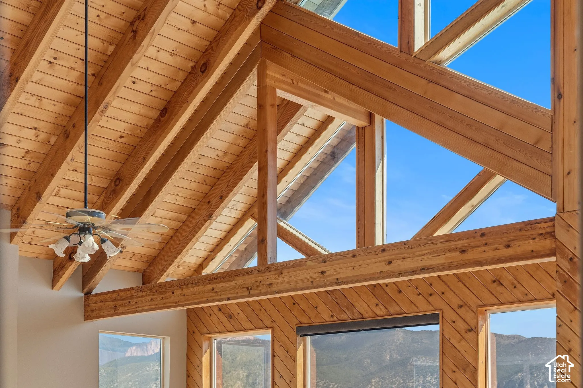 Vaulted wood-paneled ceiling, exposed wood beams, and a decorative ceiling fan