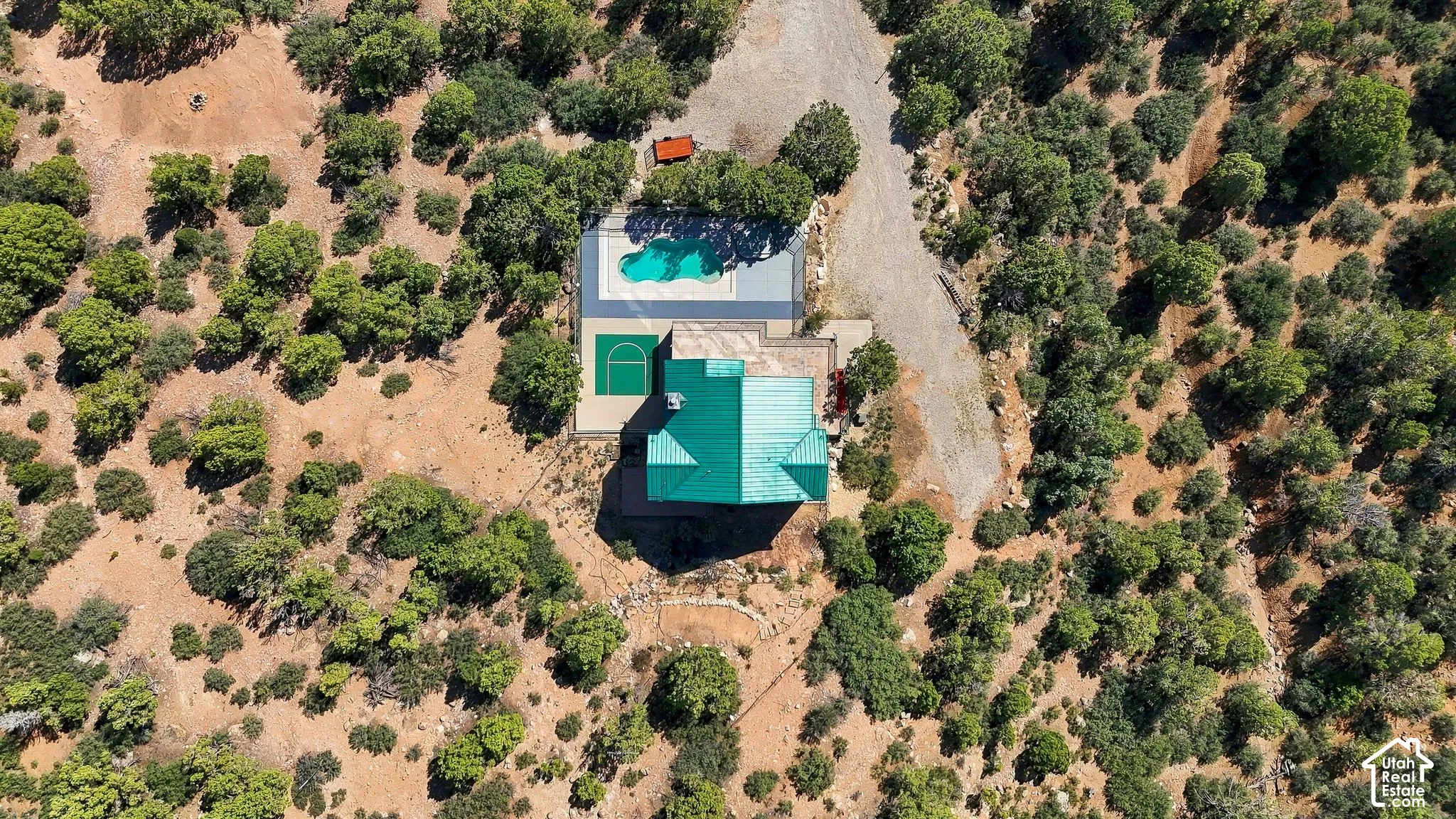 Aerial view showcasing a modern residence with turquoise pool and spa nestled within mature landscaping