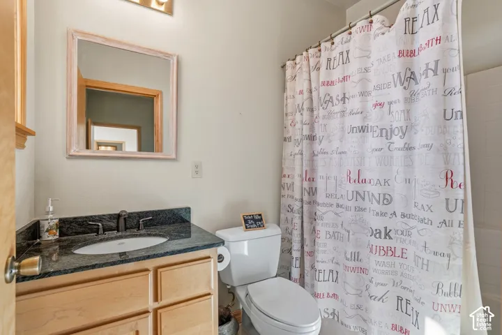 Bathroom featuring a wood-finish vanity with a built-in sink, dark countertop, and dark-toned faucet