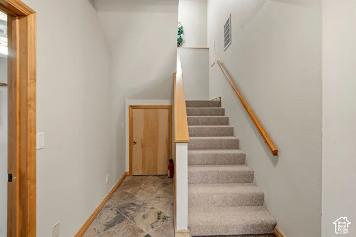Carpeted staircase with wood handrail