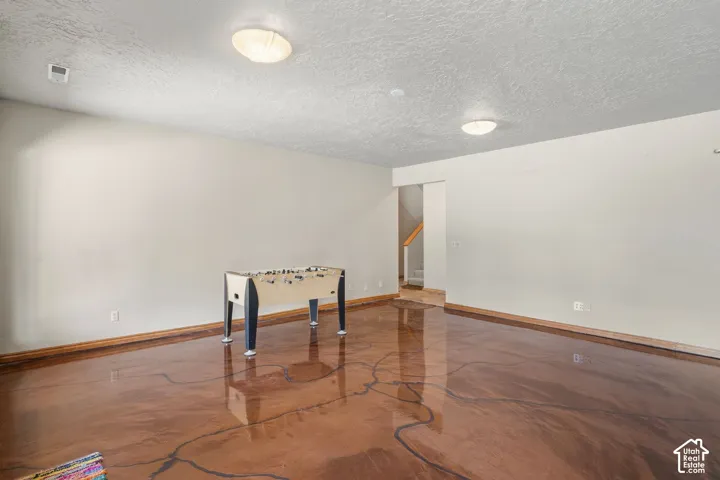 Spacious room featuring a polished concrete floor, light-toned walls, and recessed lighting