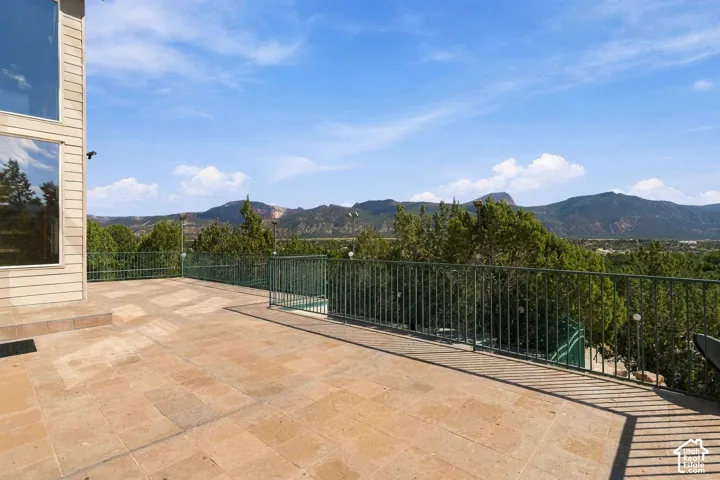 Expansive stone-paved terrace overlooking manicured landscaping and forested mountain ranges