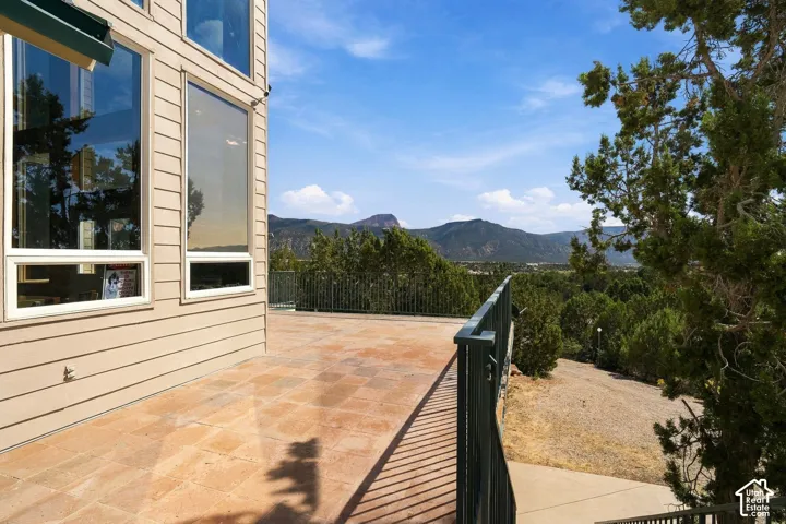 Expansive composite deck with mountain vistas, featuring terracotta-toned flooring and black metal railing