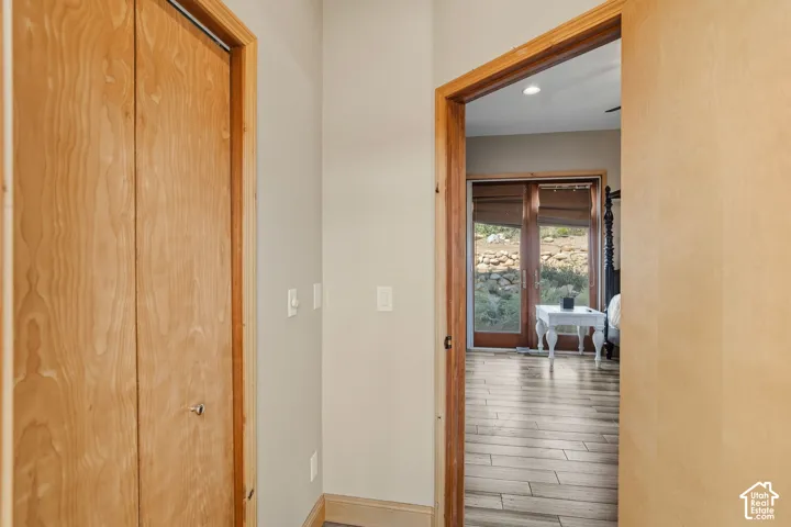 Hallway featuring warm wood-finish doors with solid frames, neutral wall finishes, and recessed lighting