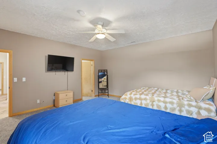 Neutral tone walls, ceiling fan with integrated lighting, and carpet flooring