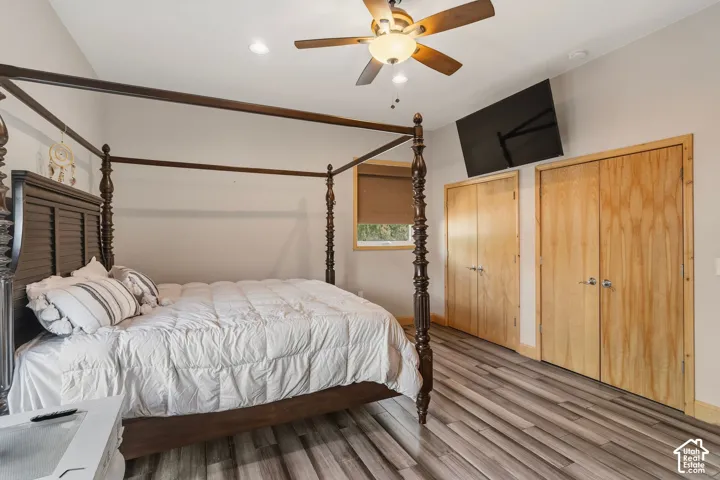 Primary Bedroom Suite with Four-Poster Canopy Bed, Ceiling Fan, Wood-Finish Flooring, and Dual Wood-Finish Closet Doors with Ample Storage Space