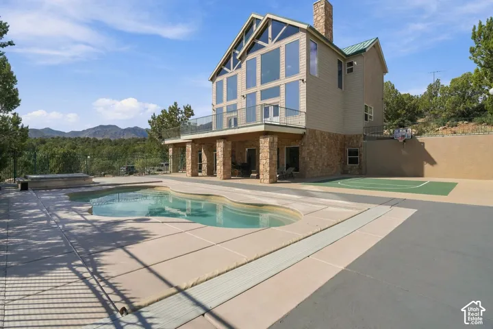 Modern Tudor-inspired residence with stucco and timber-frame detailing, showcasing a resort-style backyard featuring a sparkling saltwater pool, spa, and expansive composite decking