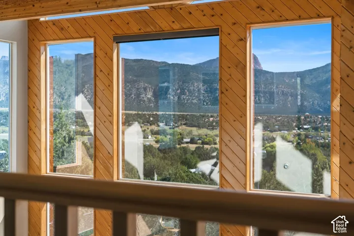 Expansive multi-panel windows frame panoramic vistas of forested mountains, a winding river, and verdant valley below