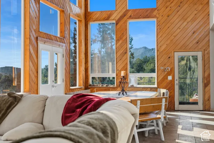 Expansive windows with mountain scenery, dual exterior doors, wood paneling, and tile flooring