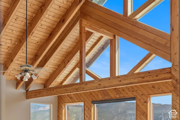 Vaulted wood-paneled ceiling, exposed wood beams, and a decorative ceiling fan