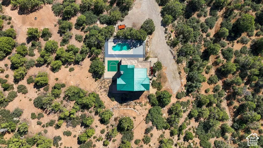 Aerial view showcasing a modern residence with turquoise pool and spa nestled within mature landscaping
