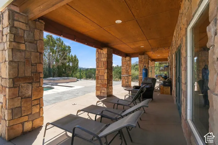 Covered patio with stone pillars, wood-finish ceiling, and recessed lighting