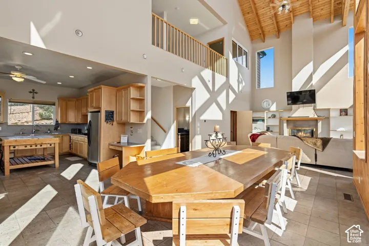 Vaulted wood-finish ceiling, exposed wood beams, fireplace with integrated shelving, and a second-story interior balcony