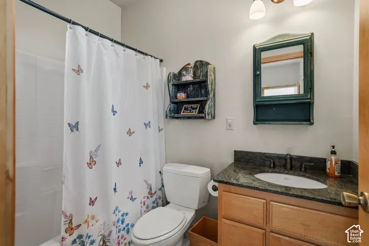 Bathroom featuring a wood-finish vanity with dark countertop and undermount sink, chrome fixtures, and abundant natural light from a window