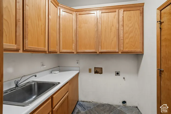 Wood-finish cabinetry, stainless steel sink, chrome faucet, white countertop, and tiled flooring