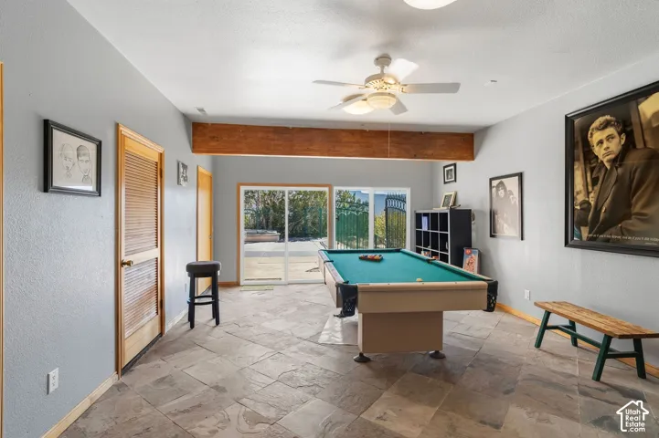 Spacious recreation room with tile flooring, ceiling fan, and glass sliding doors opening to outdoor space