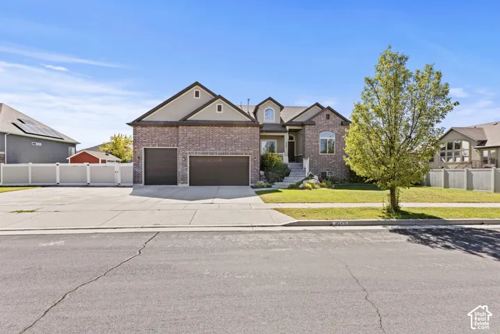 Brick and siding exterior with a two-car garage, concrete driveway, and a manicured lawn
