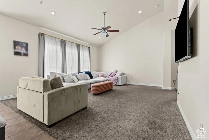 Vaulted ceiling with a ceiling fan, recessed lighting, expansive windows, and wall-mounted television