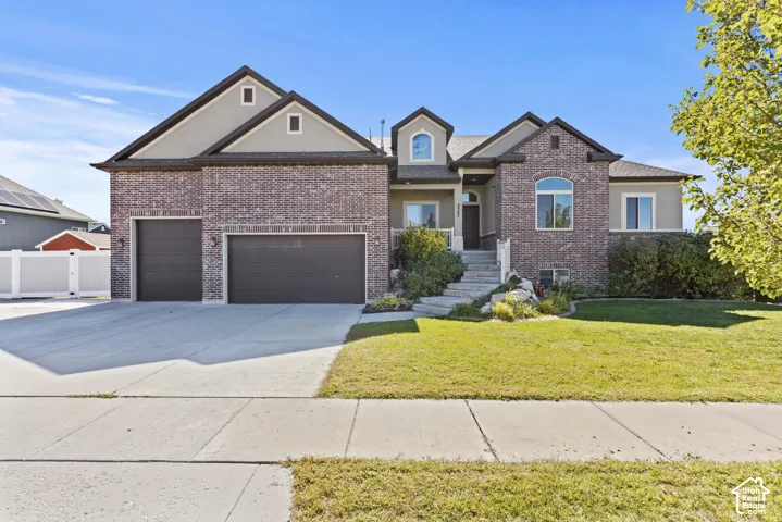 Brick and stucco exterior, arched windows, covered entry, front porch with railings, and a two-car garage