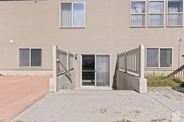 Patio with a concrete surface, a sliding glass door entry, and two sets of stairs with railings leading to a lower level