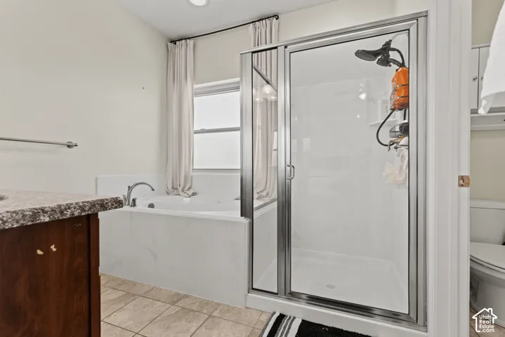 Walk-in shower with glass enclosure, separate bathtub with window, and a vanity with a stone-finish countertop