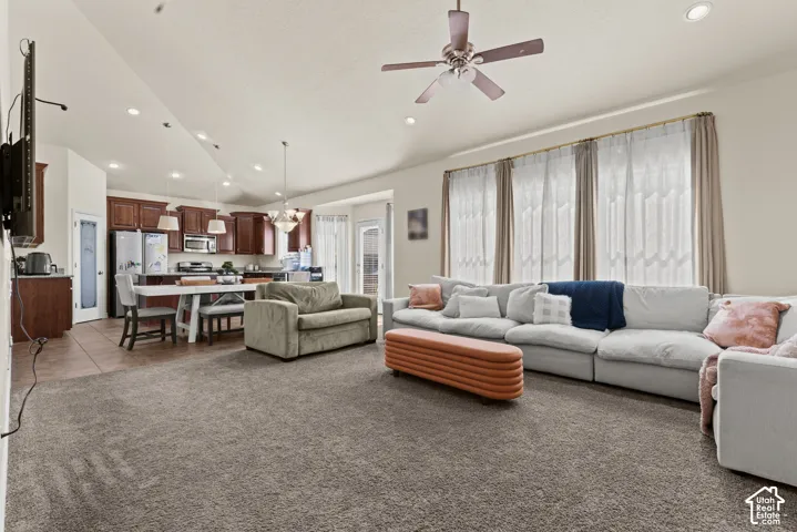 Open-concept living area featuring extensive natural light from sliding glass doors and transom windows, neutral carpeting throughout, recessed ceiling lighting, and ceiling fan