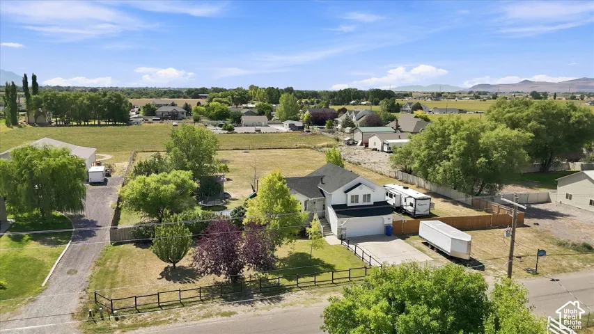 White two-story residence with an attached garage, featuring a dark roof and a paved driveway