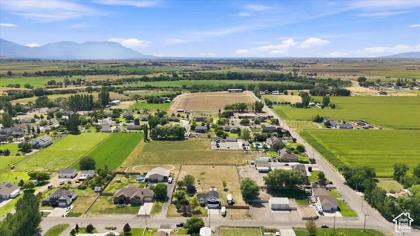Expansive rural property featuring multiple residences and outbuildings nestled across verdant acreage, with mature tree-lined perimeters, organized landscaping, and distant mountain vistas